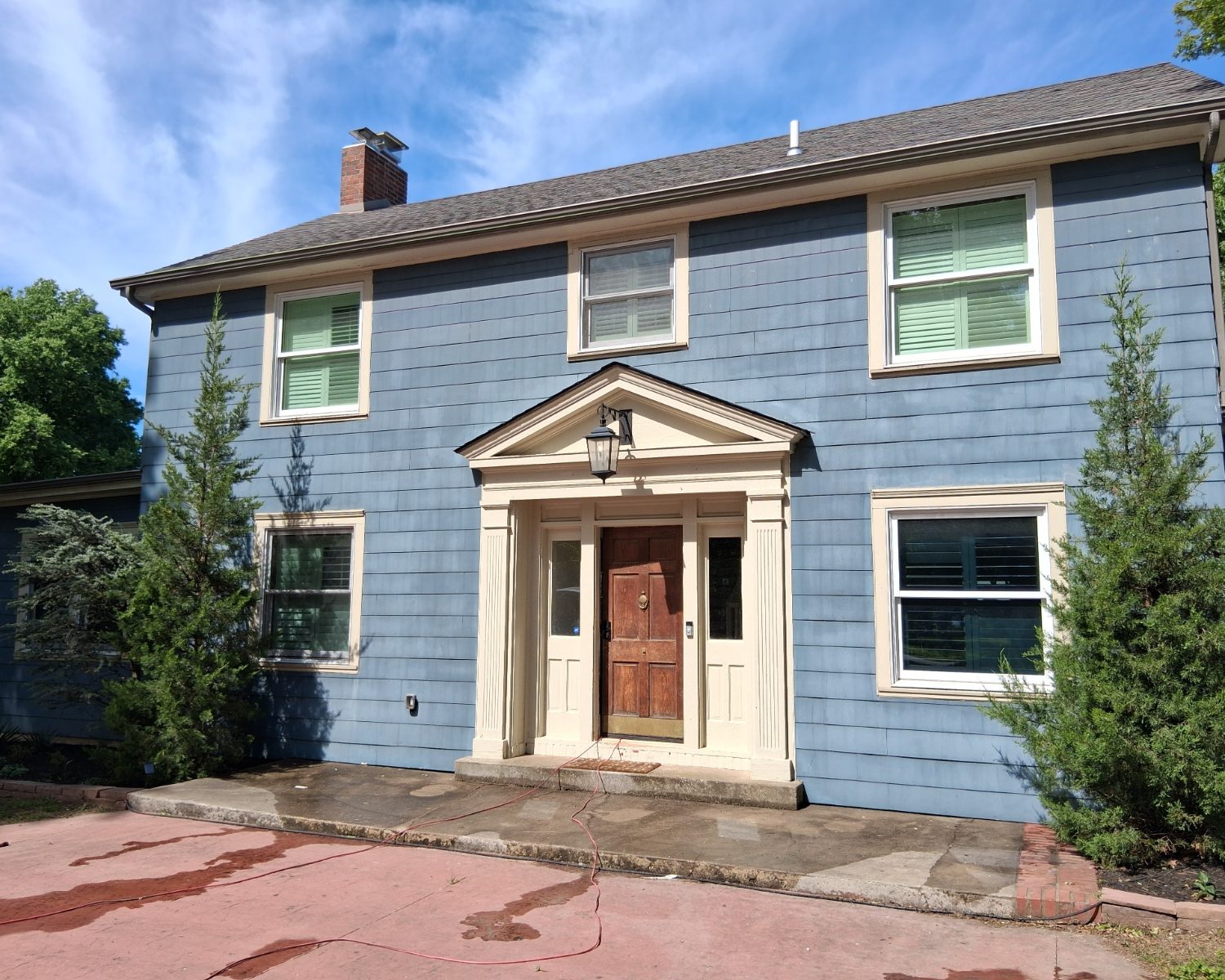 Two-story blue home with cream trim and a red front door, exterior repainted by ColorTrends Painting