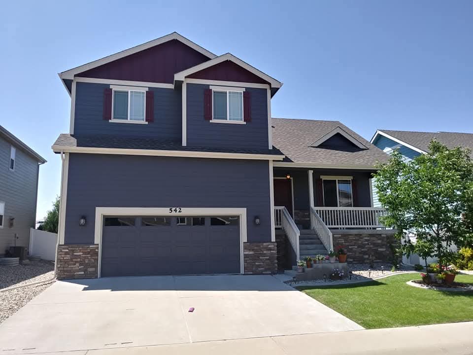 Freshly repainted two-story navy home with stone accents and a red door in Springfield, MO by ColorTrends Painting