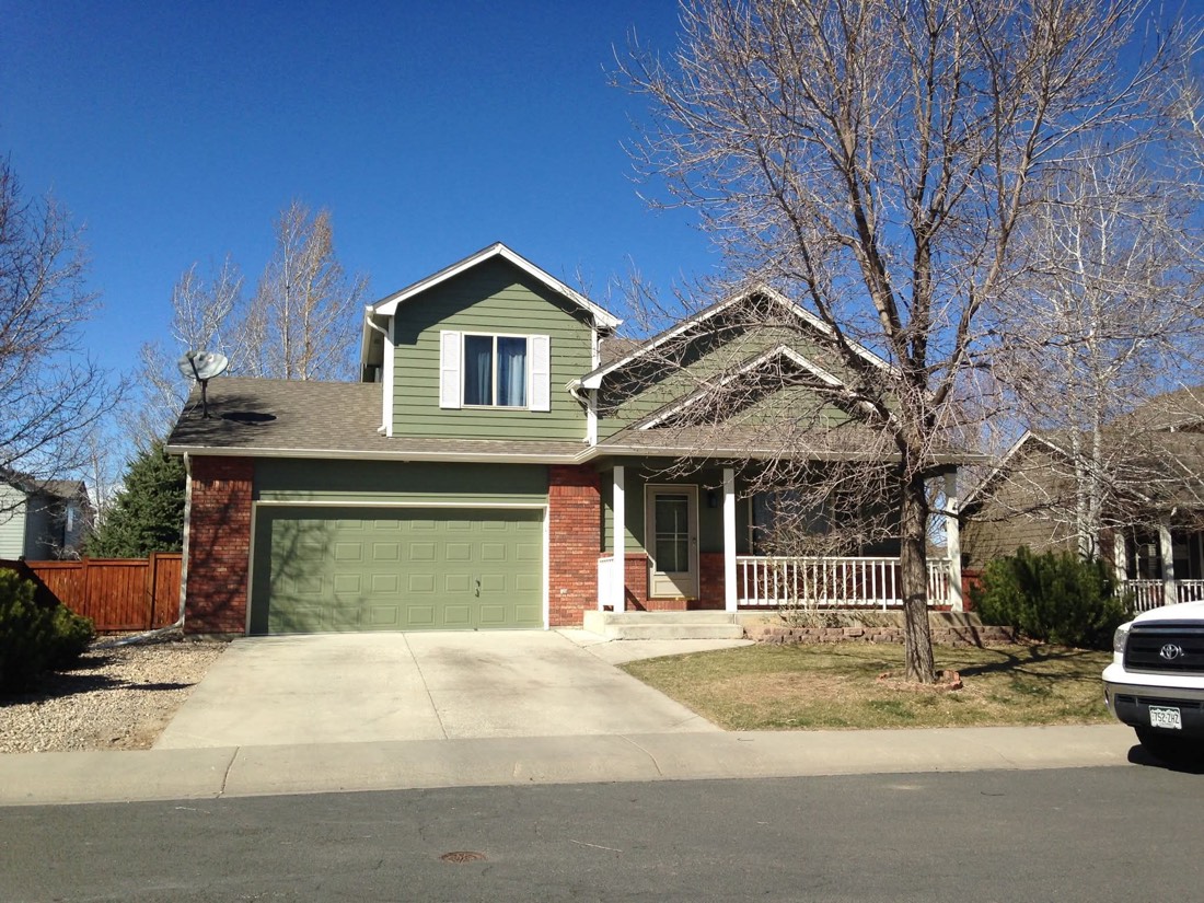 Two-story home with fresh green siding, brick accents, and white trim, freshly repainted